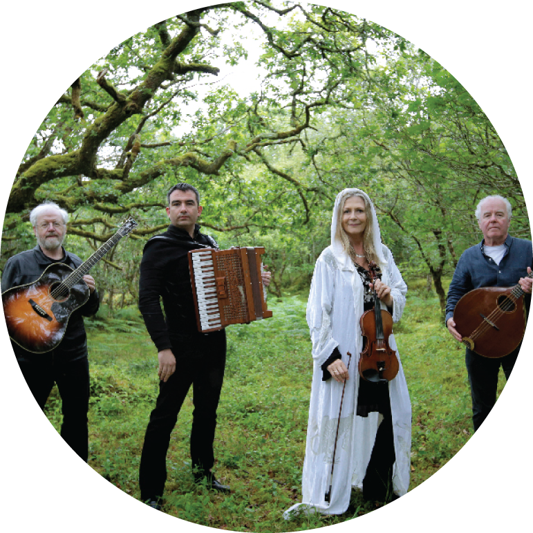 Altan holding their instruments and looking at camera in a forest