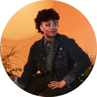 Amythyst Kiah poses by a sunset orange background,