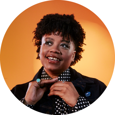 Amythyst Kiah fixes her ties against a sunset orange background.