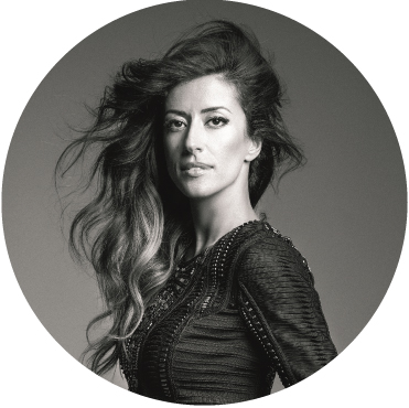Black and white photo of Ana Moura where her body is turned to the side but her face is facing straight ahead into the camera with her hair flipped all to the right