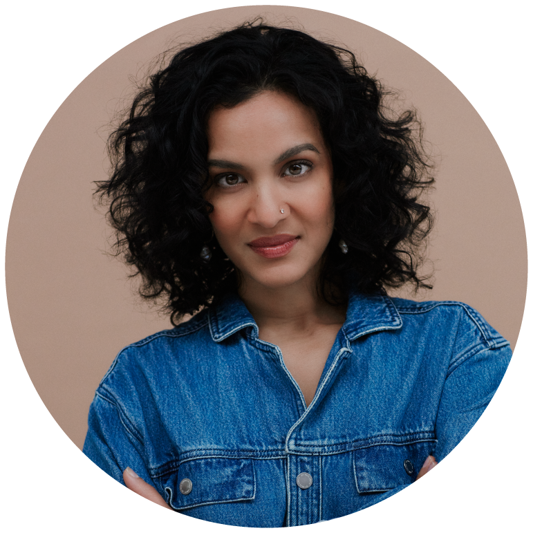 Anoushka Shankar sits in front of a beige backdrop in a denim top