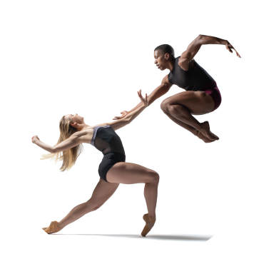 Two dancers wearing black leotards are in front of a white background. One has long blond hair and is crouching and leaning backwards. The other has short black hair and is in the air with their legs tucked in and toes pointed.