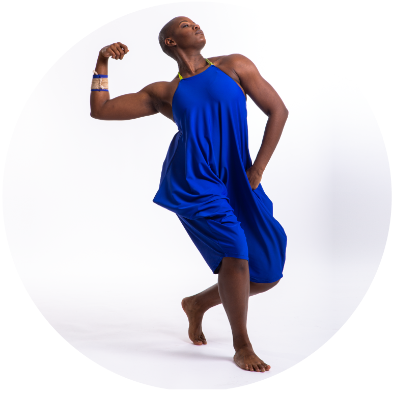 A dancer in a blue outfit stands with knees bent and right arm extended in a muscle pose.