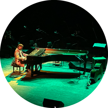 Someone playing the piano on a stage lit in green.