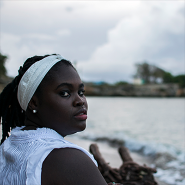 Dayme Arocena looking back into camera by water