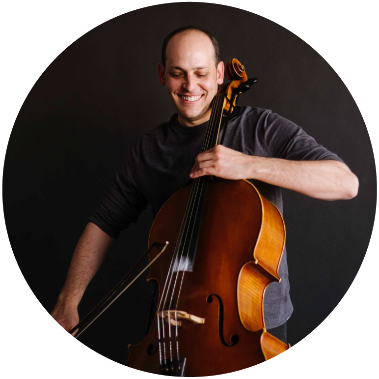 Mike Block wears a black tshirt and stands against a grey backdrop holding his cello