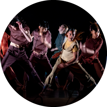 Five dances perform on a dimly lit stage.