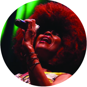 Close up of Fantcha singing passionately into a microphone with her eyes closed
