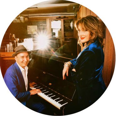 Two members of the band pose around a piano