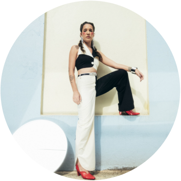 iLE poses against a blue and white backdrop wearing black and white clothing