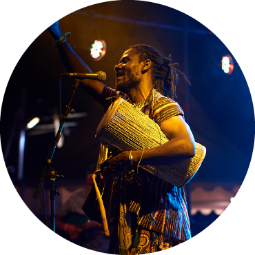 Mohammed Alidu holds a drum and speaks into a mic.