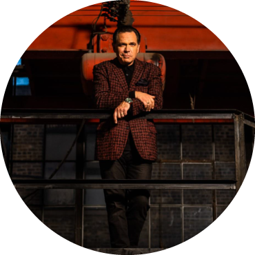 Kurt Elling stands on a platform in a warehouse wearing a suit