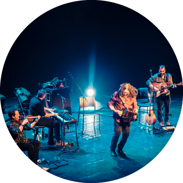 Members of Le Vent du Nord play instruments on stage.