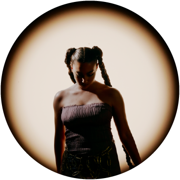 María José Llergo is spotlighted against a beige background looking down wearing a sleeveless top.