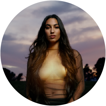 María José Llergo poses outdoors in front of the dim light of dawn.