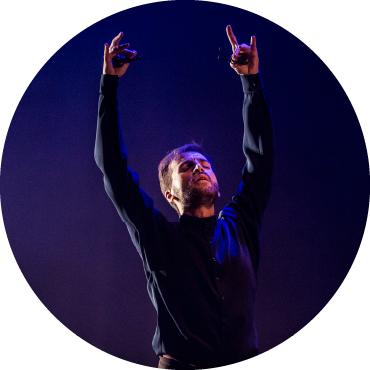 Marco Flores holds his arms up on stage.
