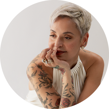 Mariza gazes to her left wearing a white dress against a white background.