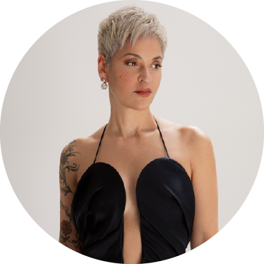 Mariza looks to the right and wears a black dress against a white background.