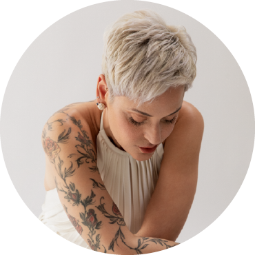 Mariza gazes down wearing a white dress against a white background.