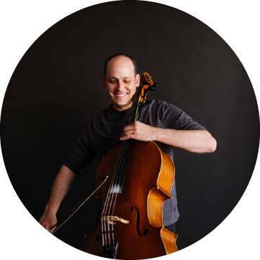 Mike Blocks smiles and looks down at his cello.