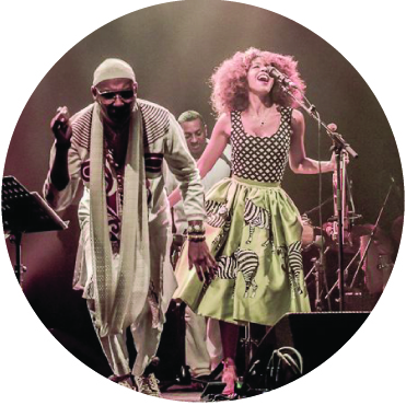Omar Sosa and Yilian Canizares performing live on stage holding hands singing to the audience