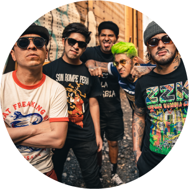 Son Rompe Pera members wear graphic t-shirts and stand together in an alleyway