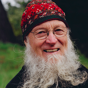 Terry Riley with red beanie smiling at camera in the woods