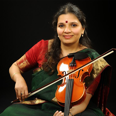 Kala Ramnath wearing traditional Indian attire while holding violin and bow in front of black background