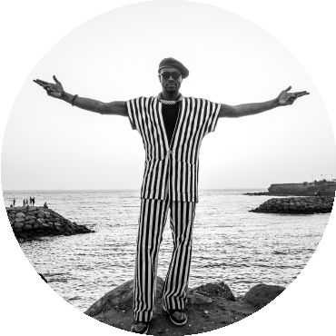 Alune Wade poses in front of water with arms open