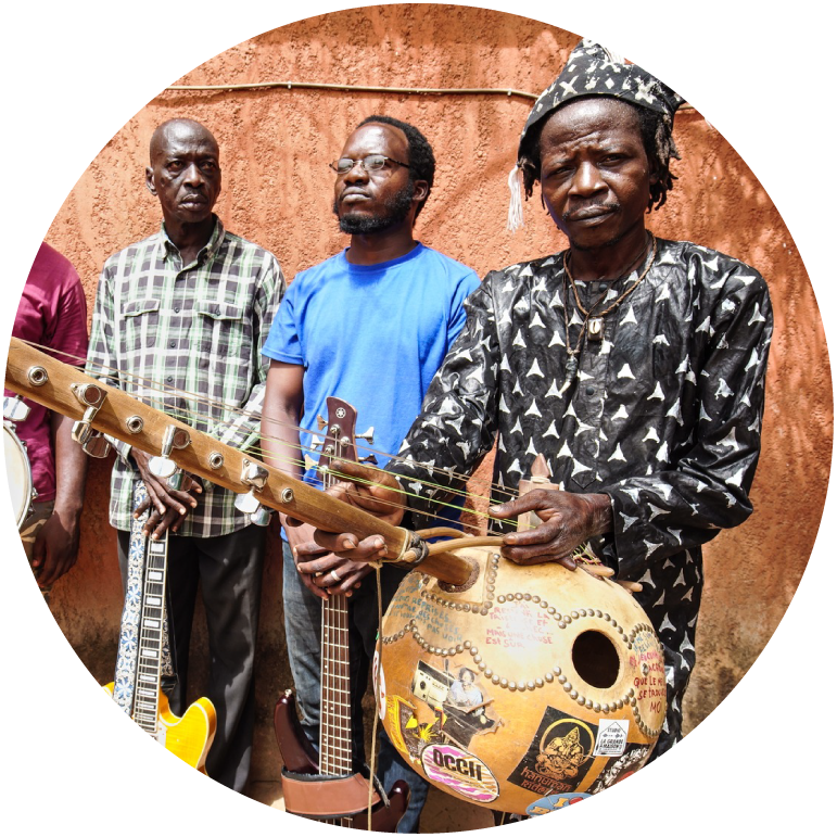 The band stands together against a brown backdrop while holding instruments