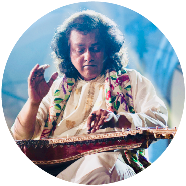 Debashish Bhattacharya wears white and plays the slide guitar