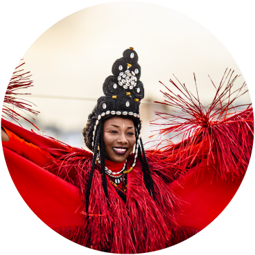 Fatoumata poses with her arms held high, wearing red traditional clothing