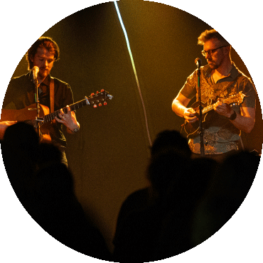 Howley performs on stage with their instruments in dim lighting