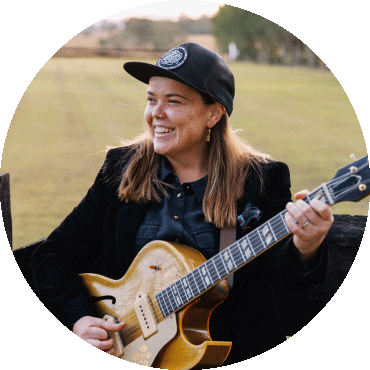 Minnie Marks smiles and holds a guitar