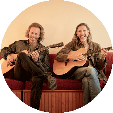 Jack West and James Nash smile and play their guitars