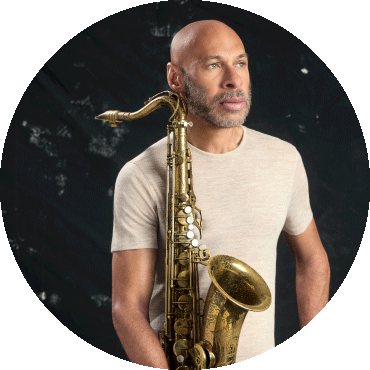 Joshua Redman poses and holds a saxophone