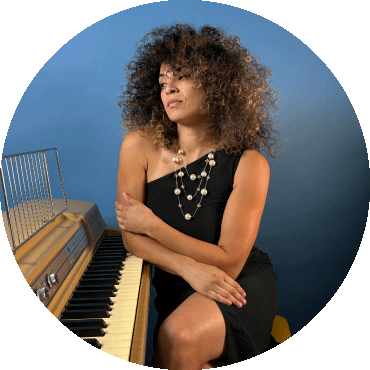 Kandace Springs posing next to a piano