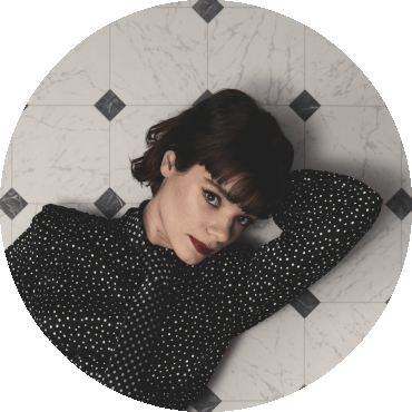 Laura Anglade lays on a tiled surface with an arm behind her head