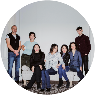 Members of Leahy sit on and around a bed while posing together against a white backdrop