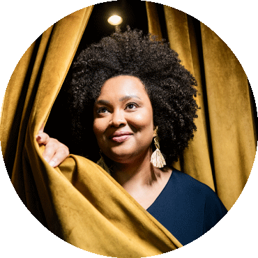 Lucibela poses holding a yellow curtain