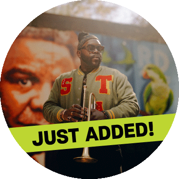 Marquis Hill stands and poses in front of a mural