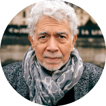 Monty Alexander looks straight at the camera wearing a gray scarf