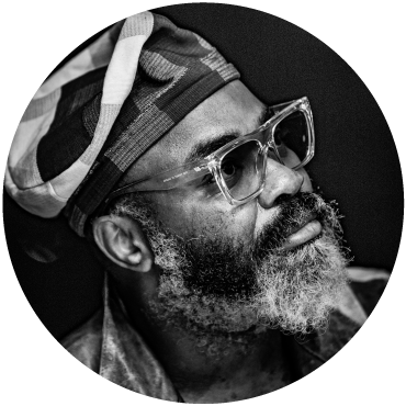 Close-cropped black and white photo of Nduduzo wearing a cap with their head titled to the right.