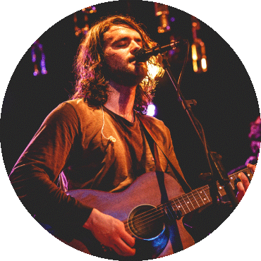 Nicolás Emden performs on stage while holding a guitar