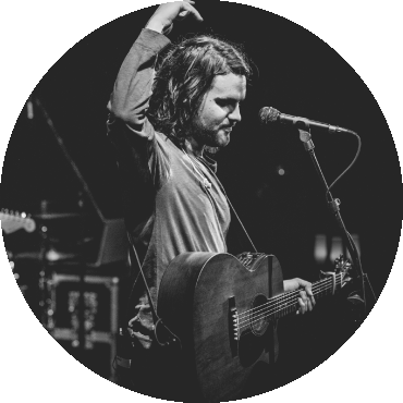 Nicolás Emden performs on stage while holding a guitar