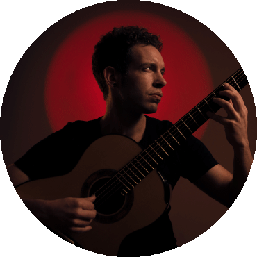 Pipo Romero holding a guitar and looking to the side against red background
