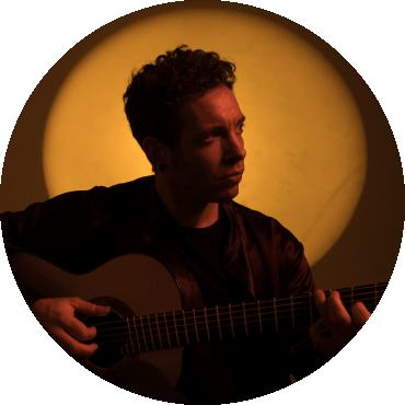 Pipo Romero holding a guitar and looking to the side