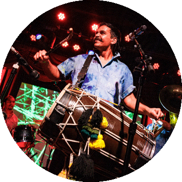 Sunny Jain smiles and plays the dhol drum