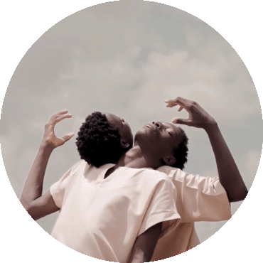 Two people lay their heads back on each other's shoulders and hold an arm up