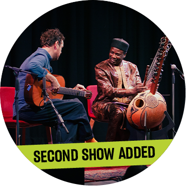Derek Gripper and Ballaké Sissoko perform on stage together holding their instruments